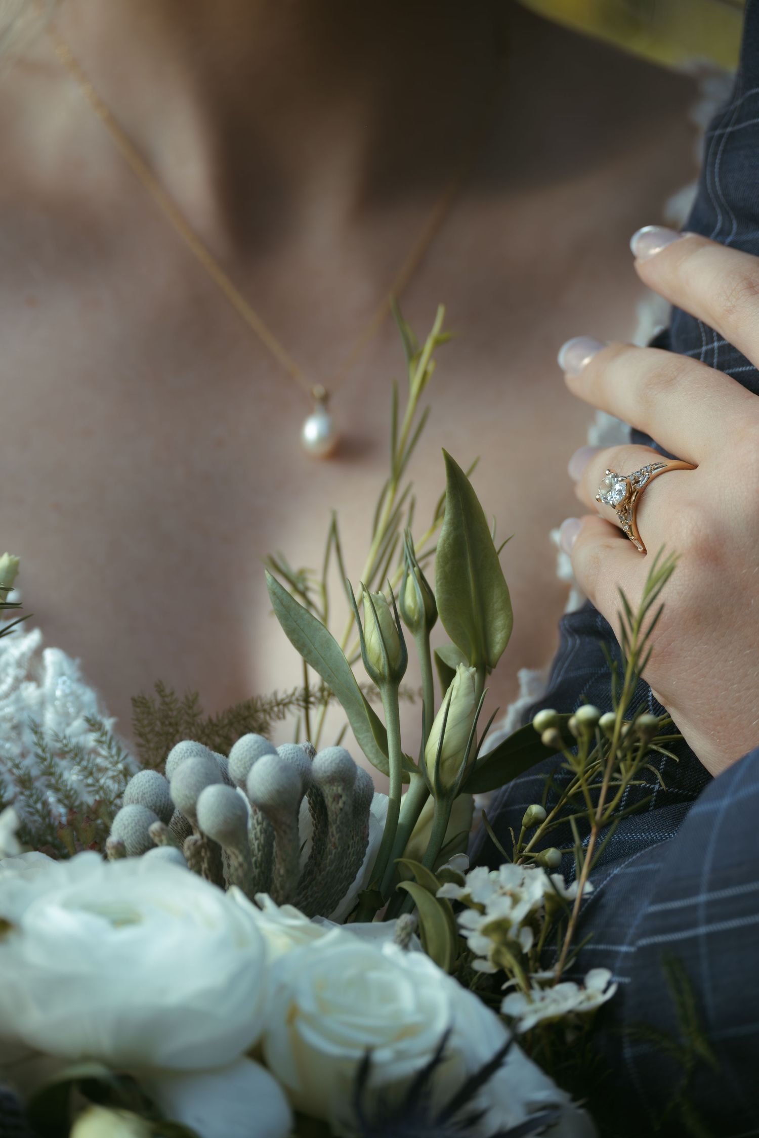 Close-up view of delicate white roses and baby's breath flowers arranged with green foliage against a soft blurred background.