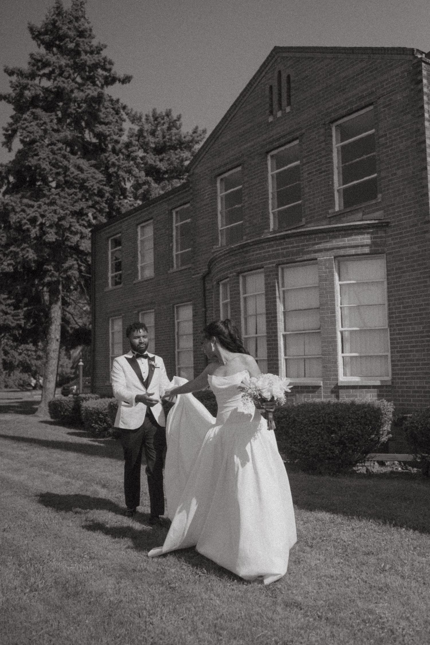 Black and white photo of a bride and groom sharing a first look outside a brick building on their wedding day.