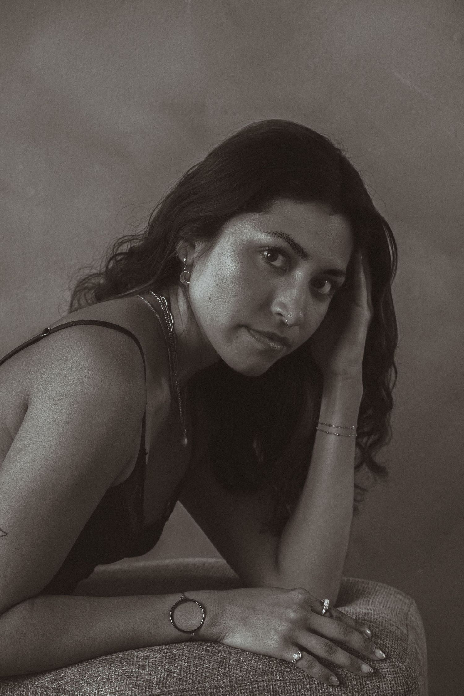 Moody black and white portrait showing contemplative pose with hand resting on face.