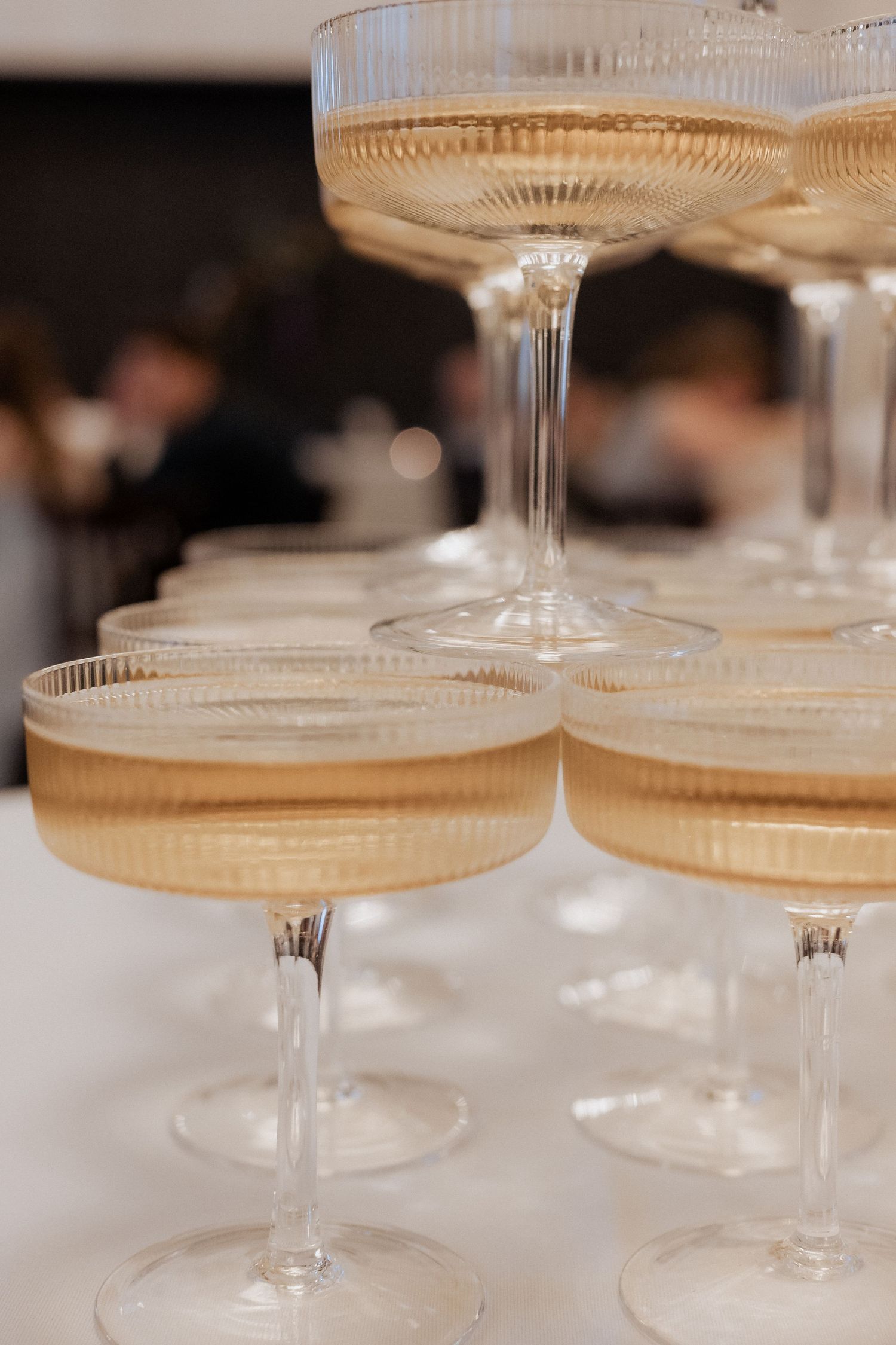 Crystal champagne coupes with elegant ribbed glass patterns arranged neatly on a white tablecloth.