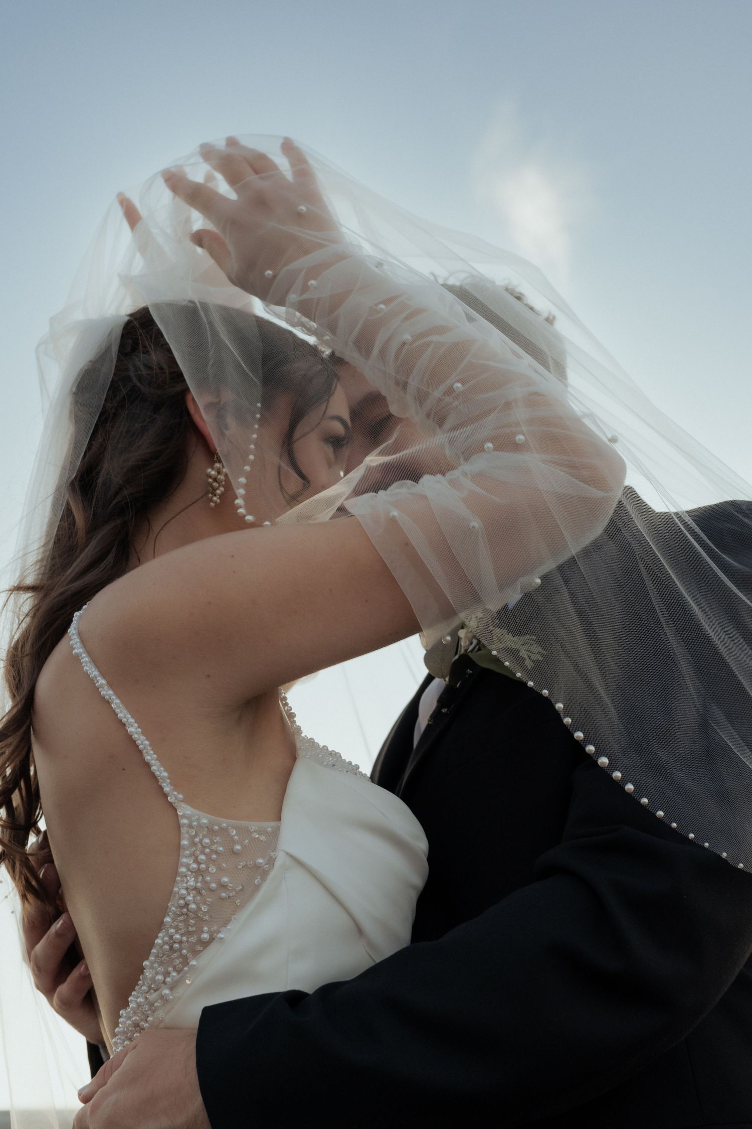 A romantic series of wedding photos showing a couple kissing under a delicate white veil.