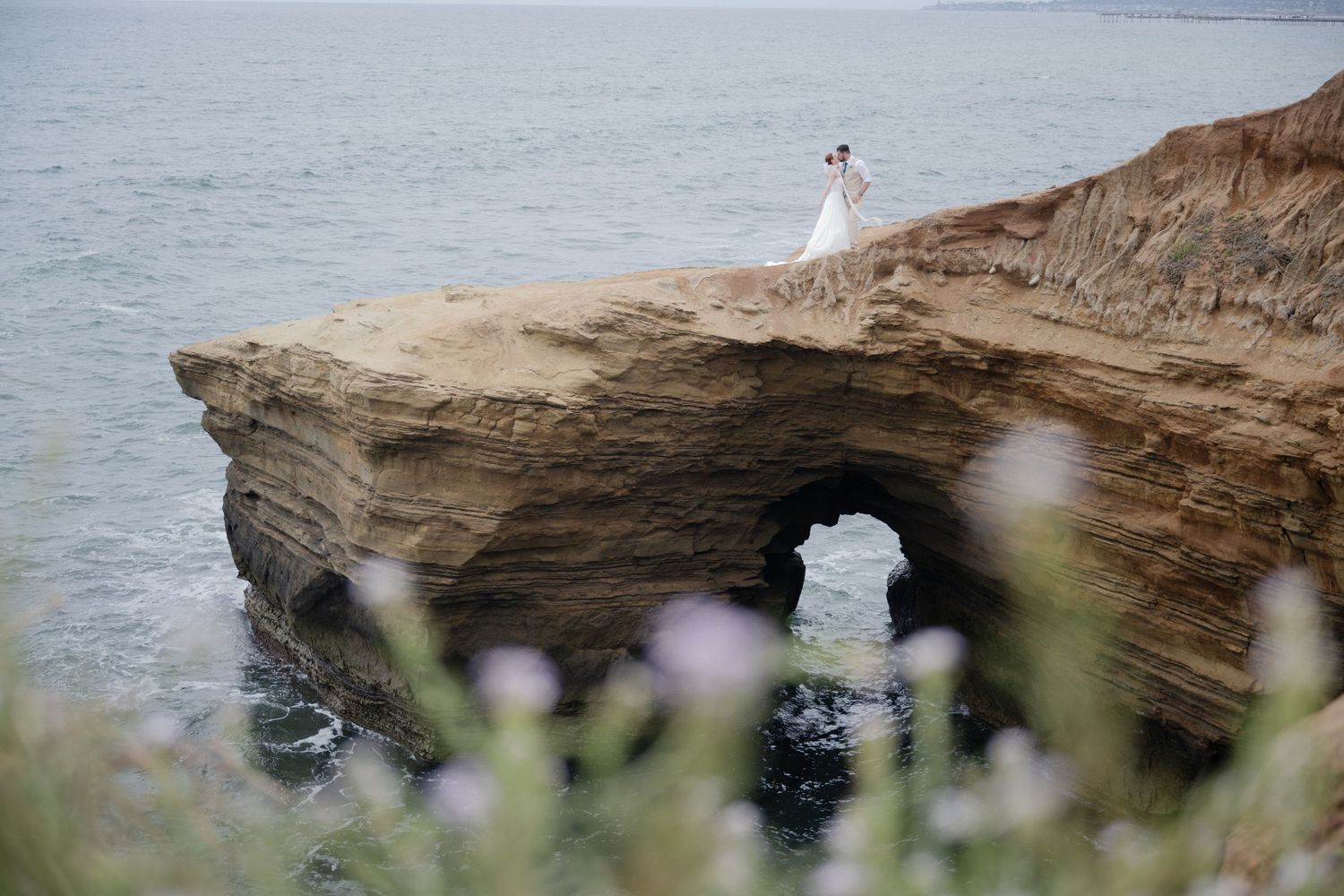 A dramatic coastal photo featuring a stone arch with someone standing atop the formation.