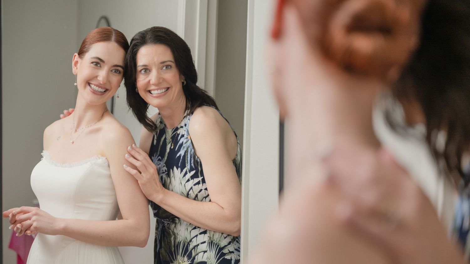 Two wedding guests share a joyful moment together in formal attire.