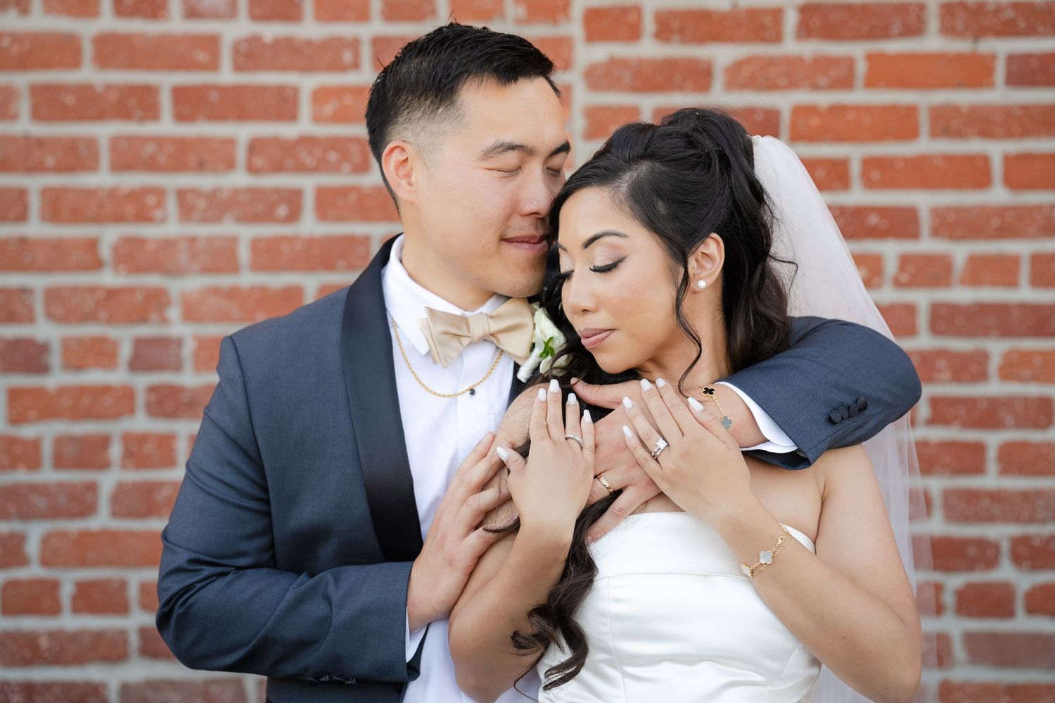 Romantic wedding portrait against rustic brick wall background.