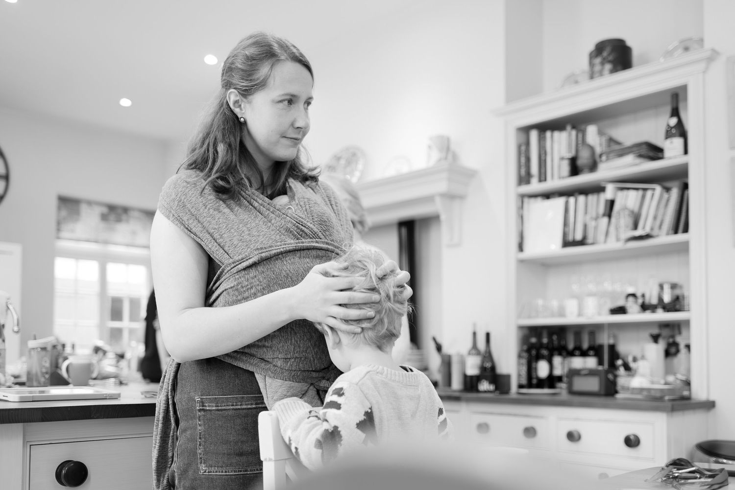 A person holds a mug of coffee while standing in a bright white modern kitchen interior.