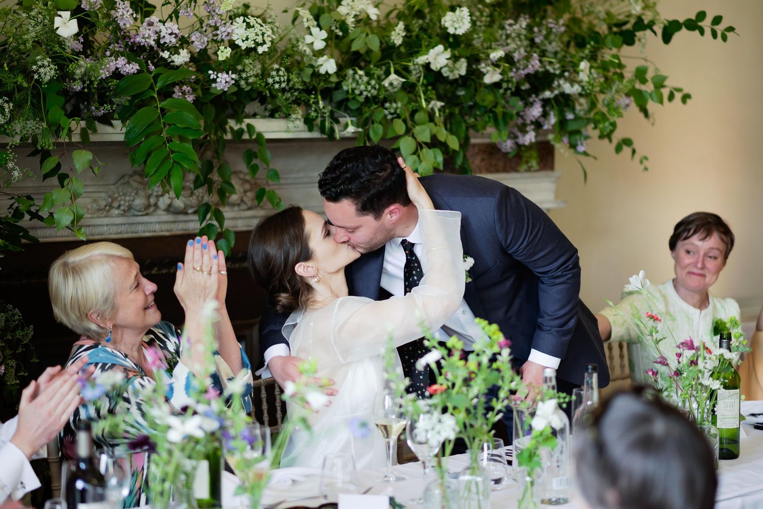 Wedding reception table decorated with floral arrangements and greenery.
