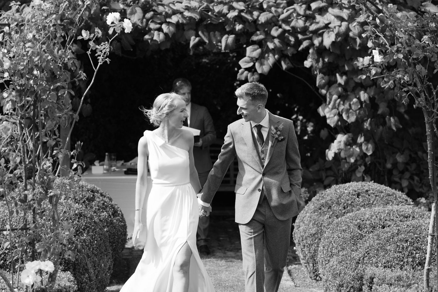 A joyful couple shares a candid moment while walking through a garden on their wedding day.