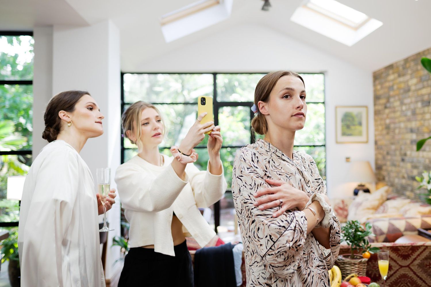 Wedding party getting ready in a bright sunlit room with skylights and brick walls.