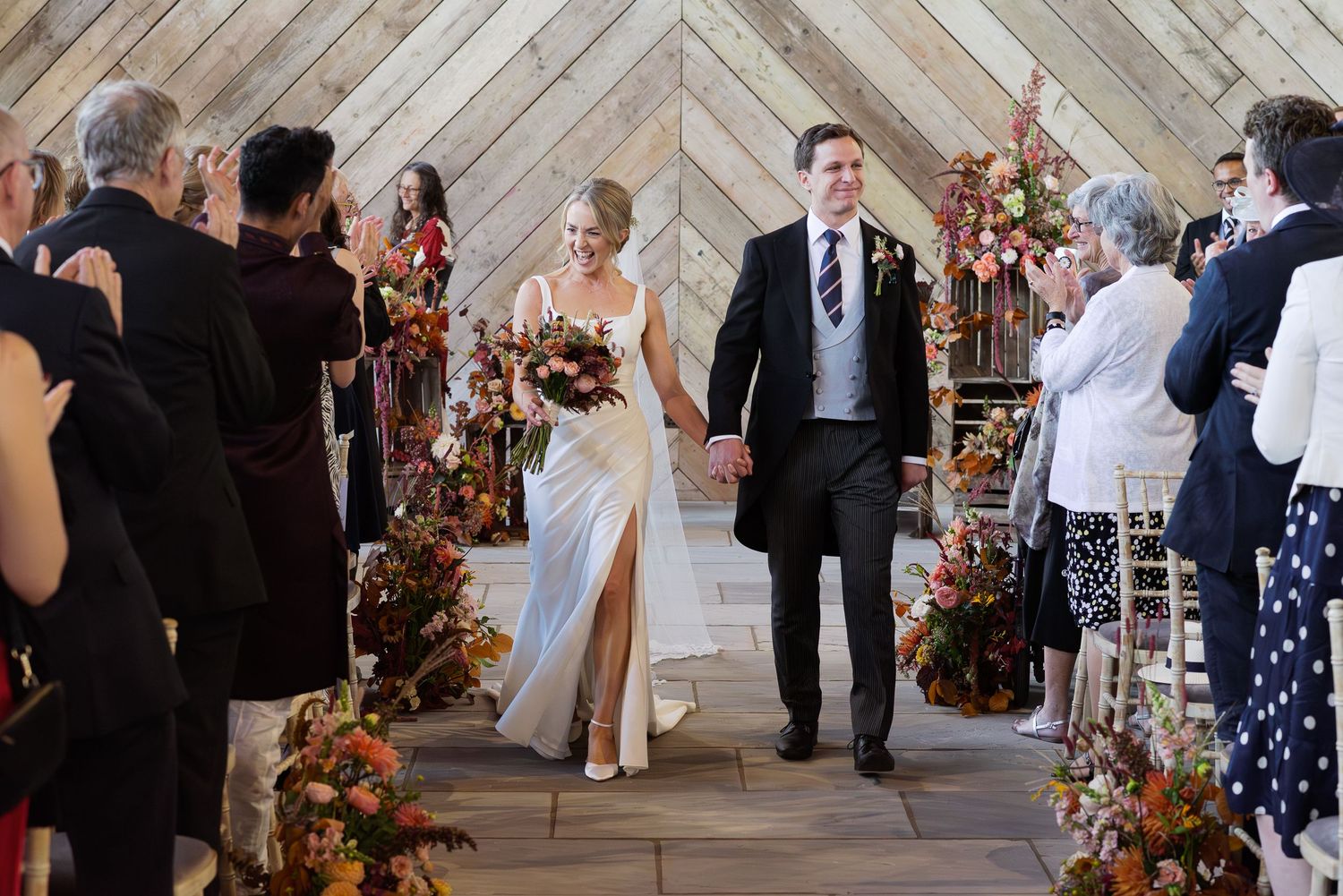 Wedding venue with diagonal wooden plank wall and floral decorations.