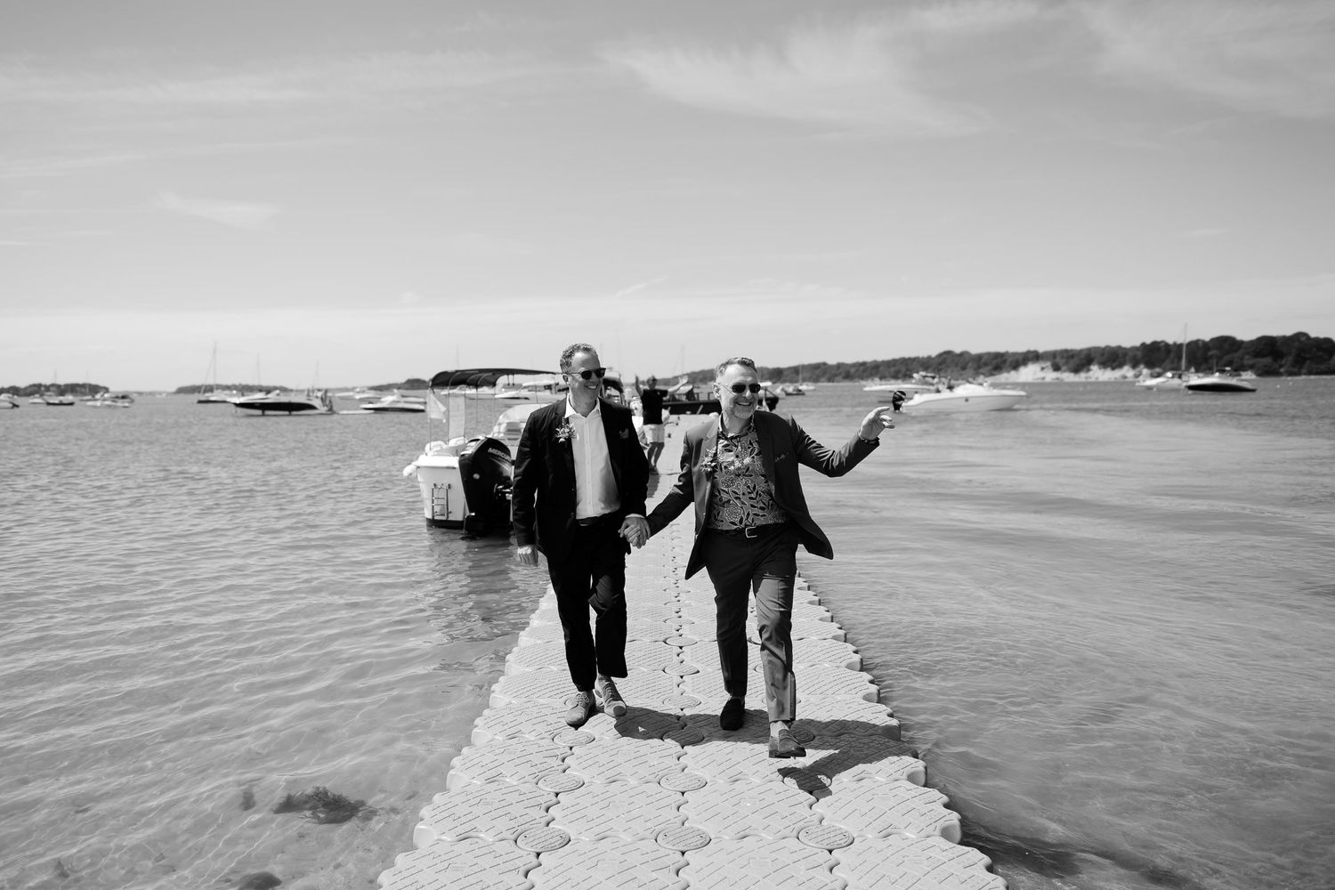 Black and white photo of two people walking along a coastal breakwater.