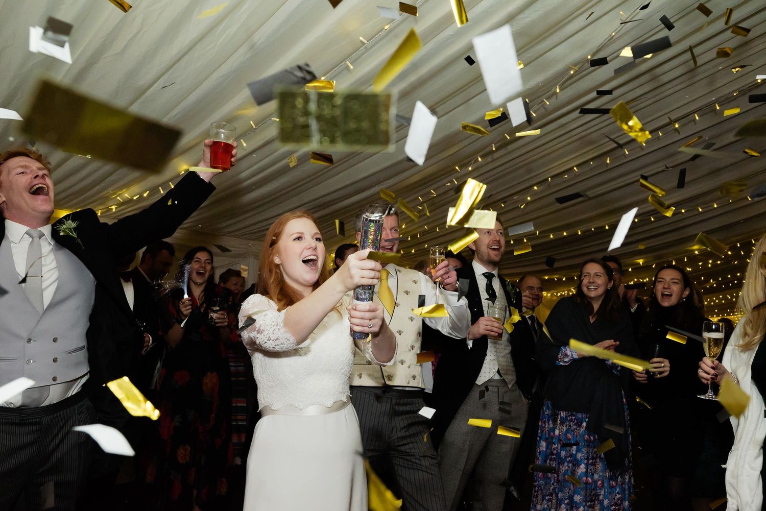 Wedding celebration with confetti being tossed in the air during a joyous reception moment.
