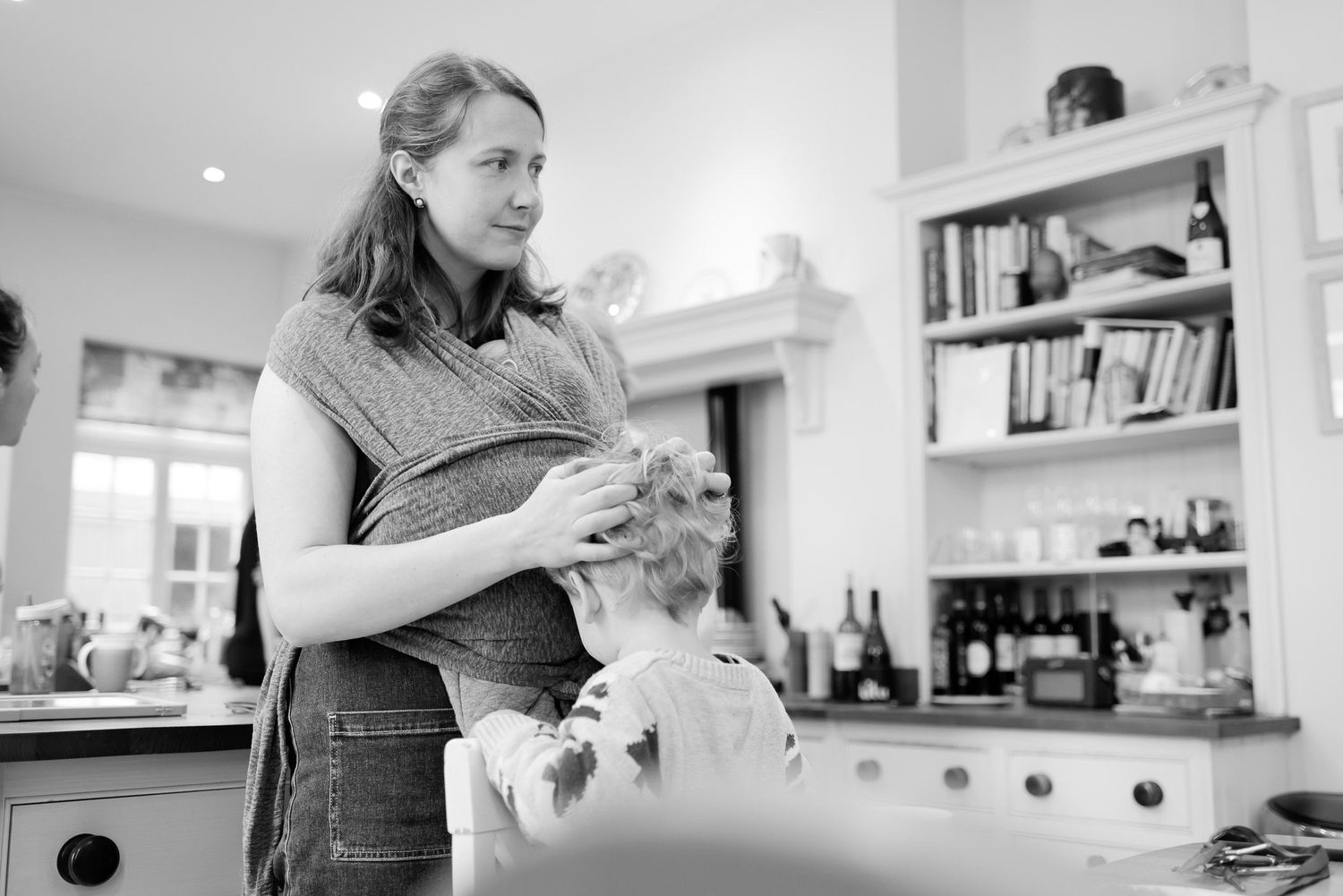 Black and white candid moment of wedding day hair styling preparation.