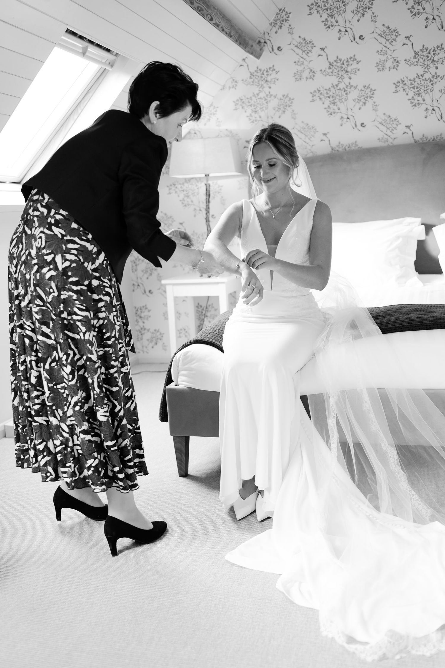 Black and white photo of final wedding preparations in elegant attic dressing room.
