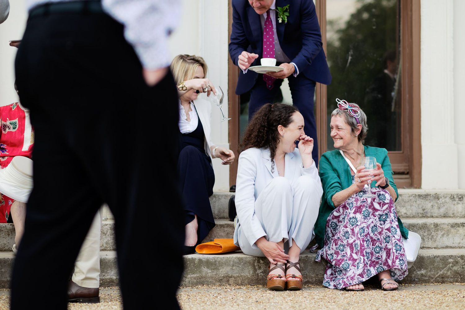 Casual gathering of guests sitting on stone steps during wedding celebration.