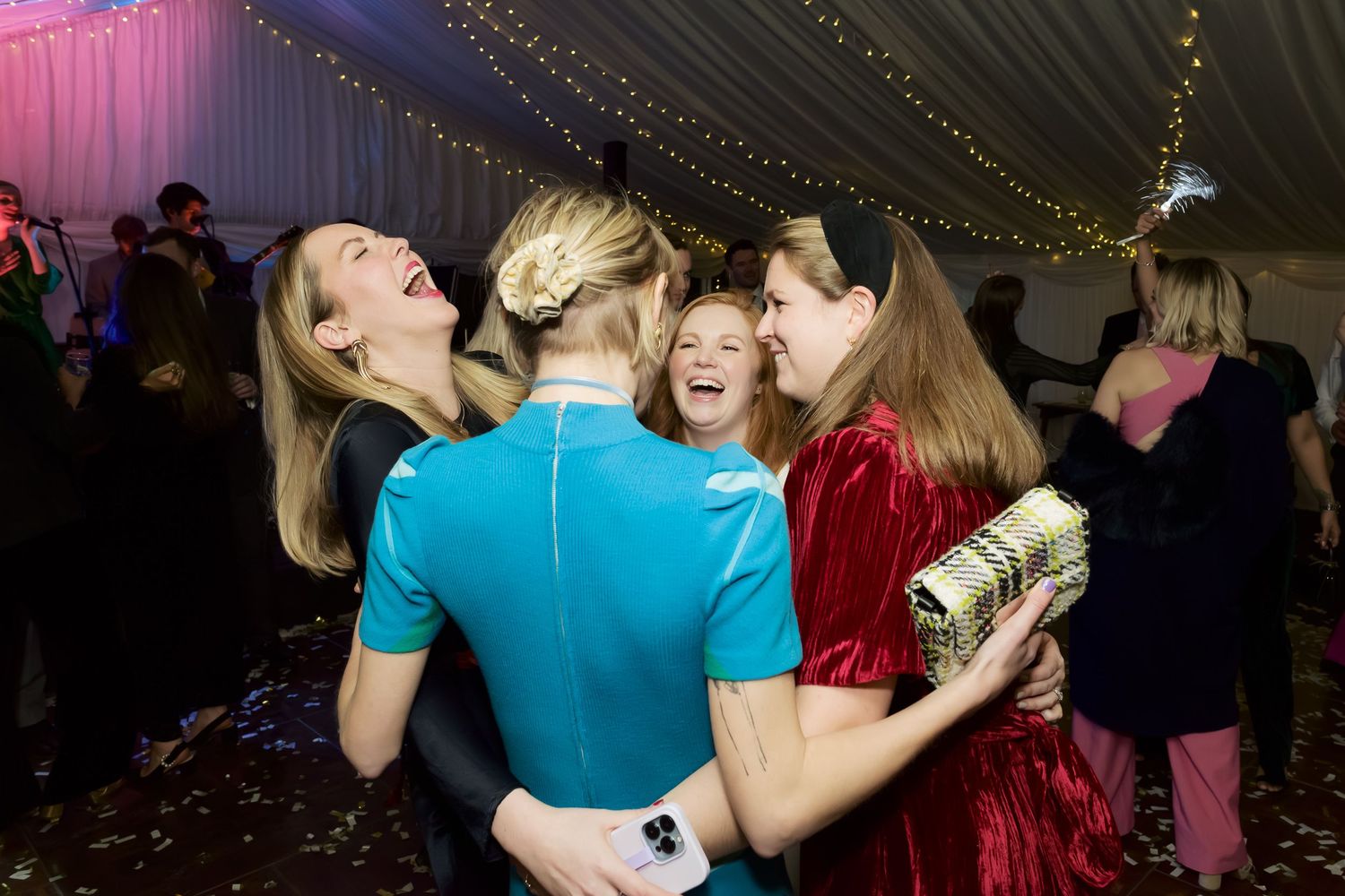 People dancing together at a dimly lit party venue with colorful lighting and decorative elements.
