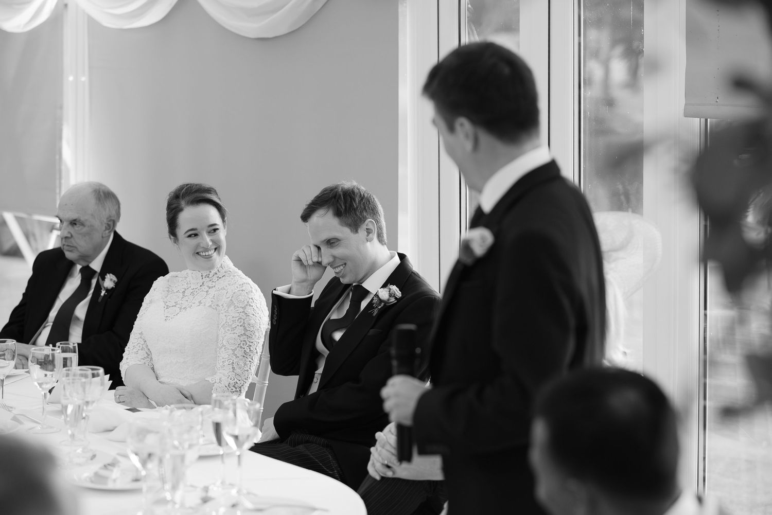 Black and white wedding reception photo showing guests seated at tables during dinner service.