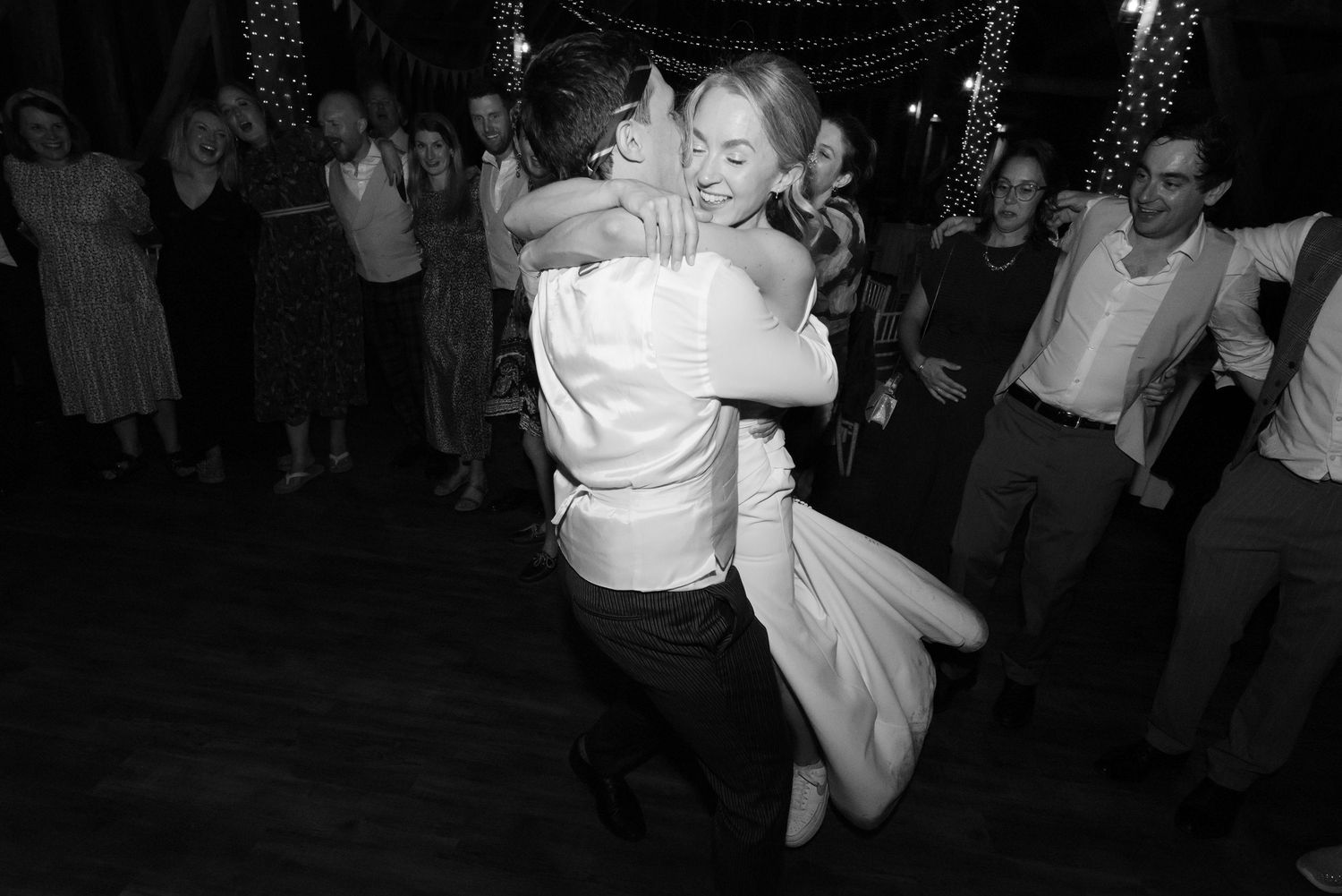 Wedding reception dance floor with guests celebrating in dark ambient lighting.