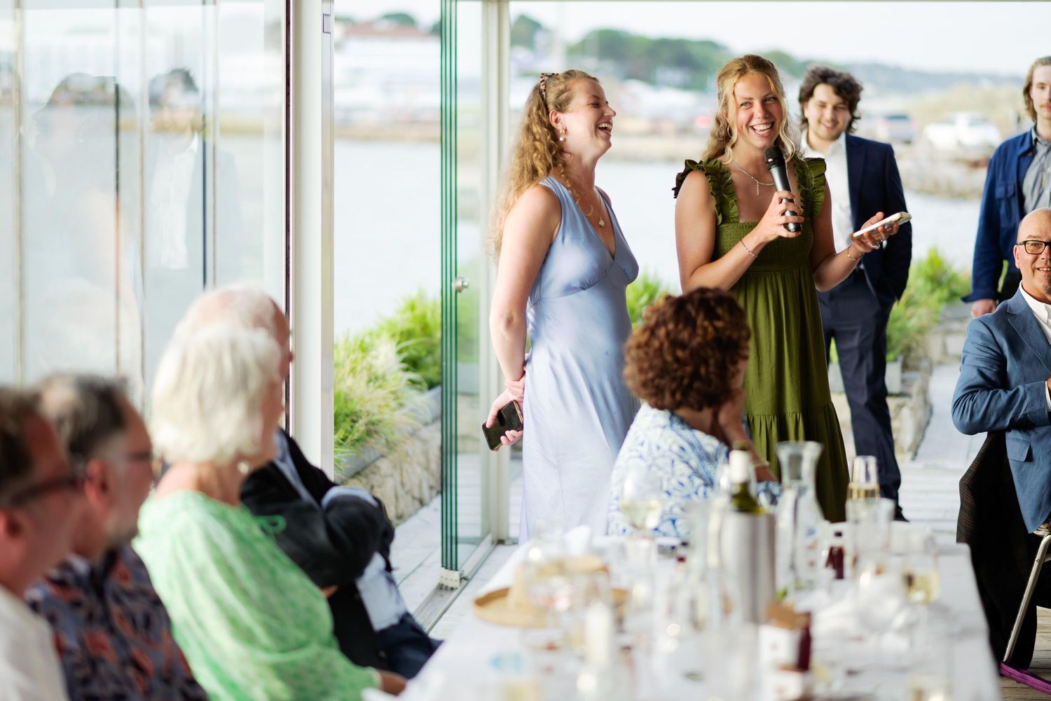 Wedding reception guests enjoying conversation and drinks at a waterfront venue.