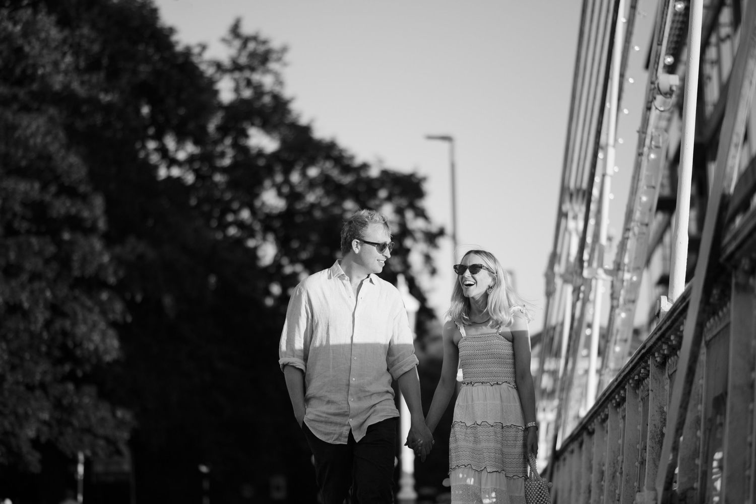 Paris and Kit walking across Chelsea Bridge, London, during their engagement session.