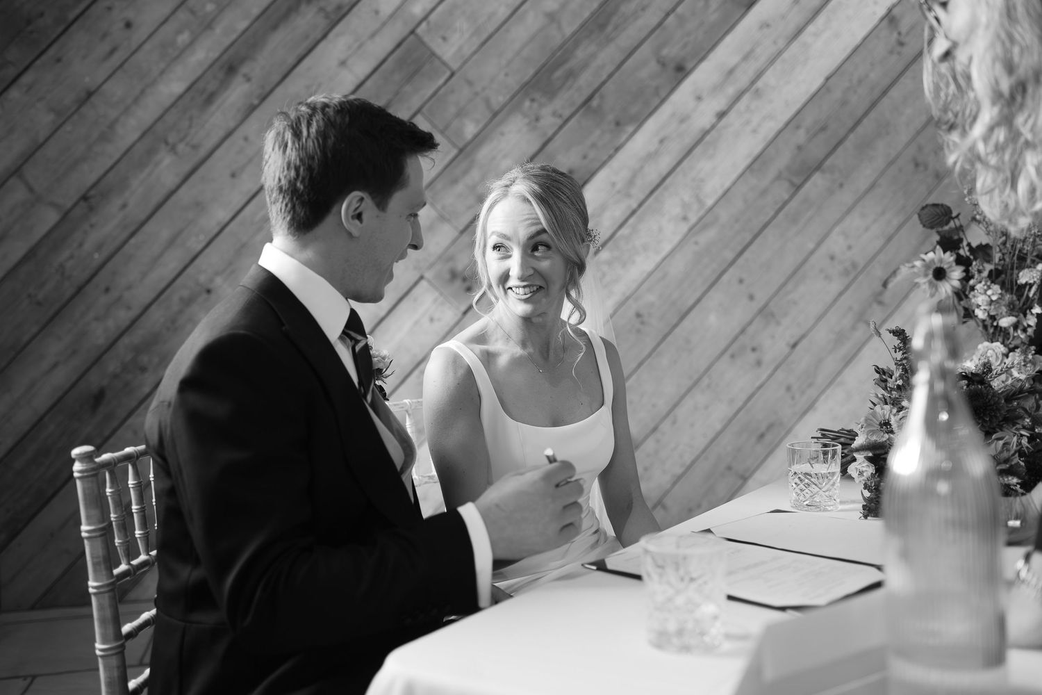Wedding reception candid moments captured in black and white photography at an indoor venue.