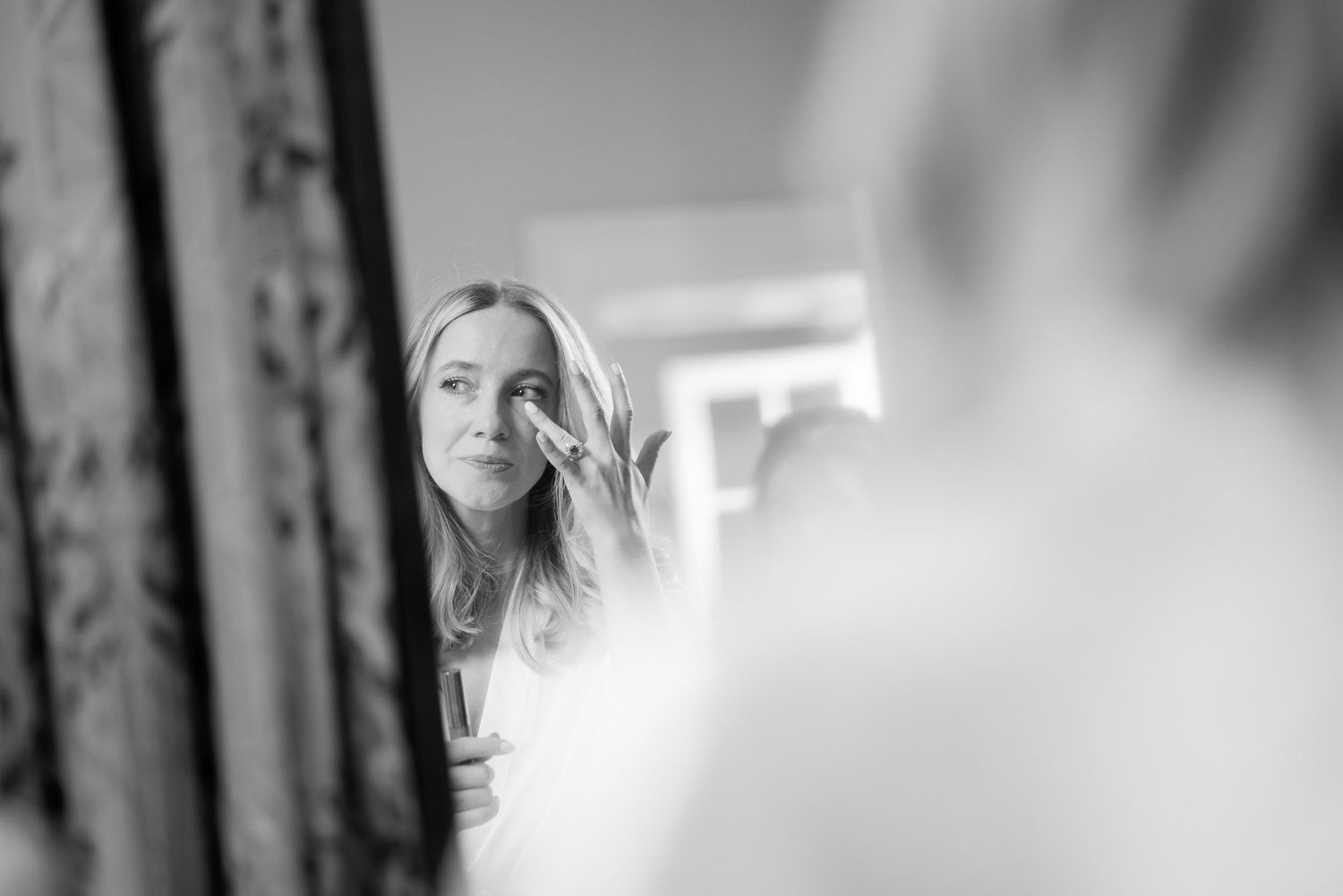 Black and white portrait capturing a soft, reflective moment in a mirror.