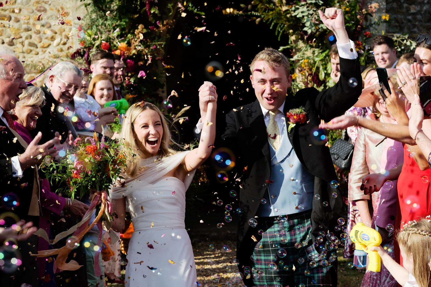 Wedding celebration with colorful confetti being thrown during a joyous outdoor celebration with guests.