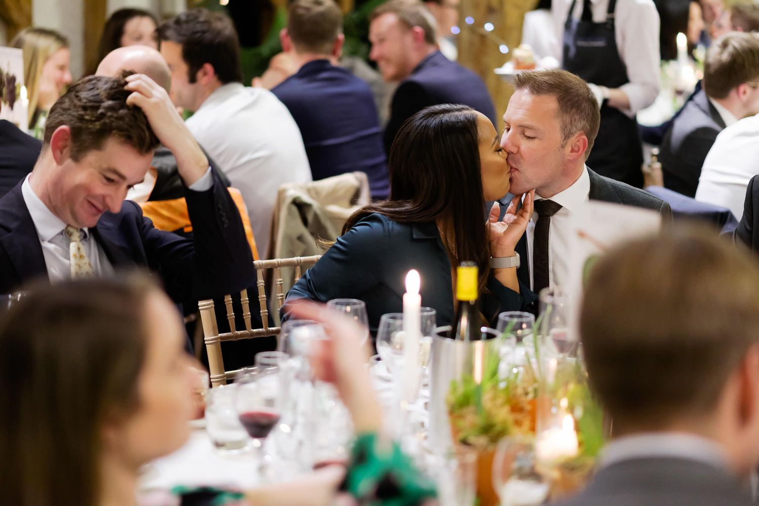 Wedding guests enjoying dinner and conversation at decorated reception tables.