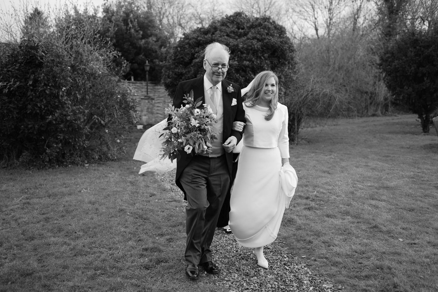 Black and white wedding photos showing a couple walking and embracing in an outdoor garden setting.
