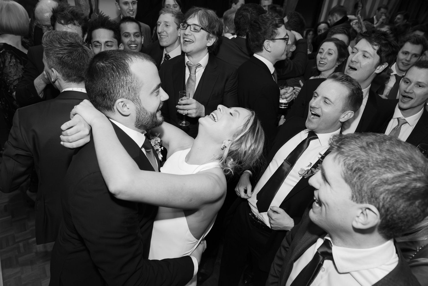 Group of people in formal attire laughing and celebrating together at a social gathering.