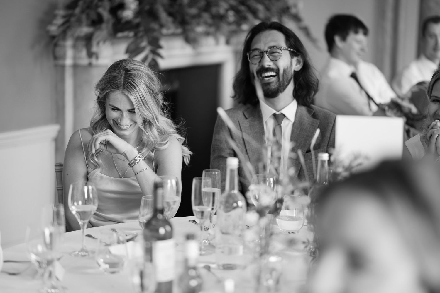 Wedding guests laughing and enjoying themselves at an elegant reception dinner table.