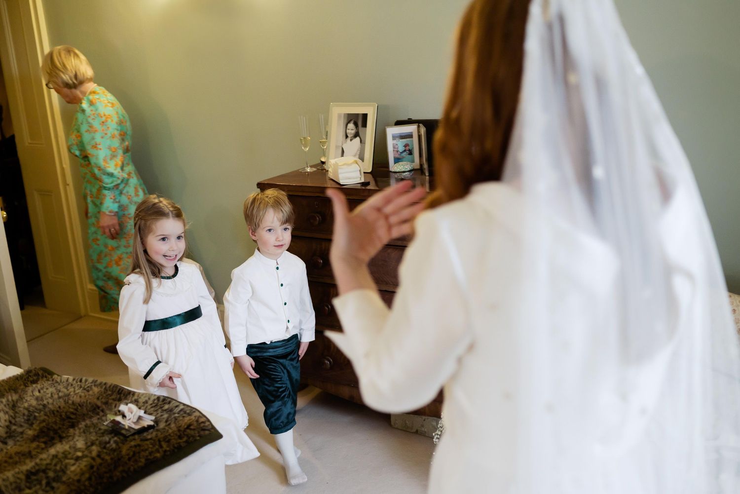 Young flower children watching as bride prepares in wedding dress.