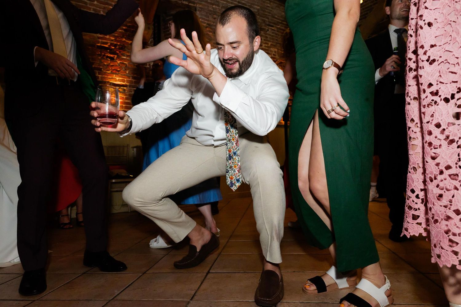 A person in white attire shows off energetic dance moves at a lively party reception.