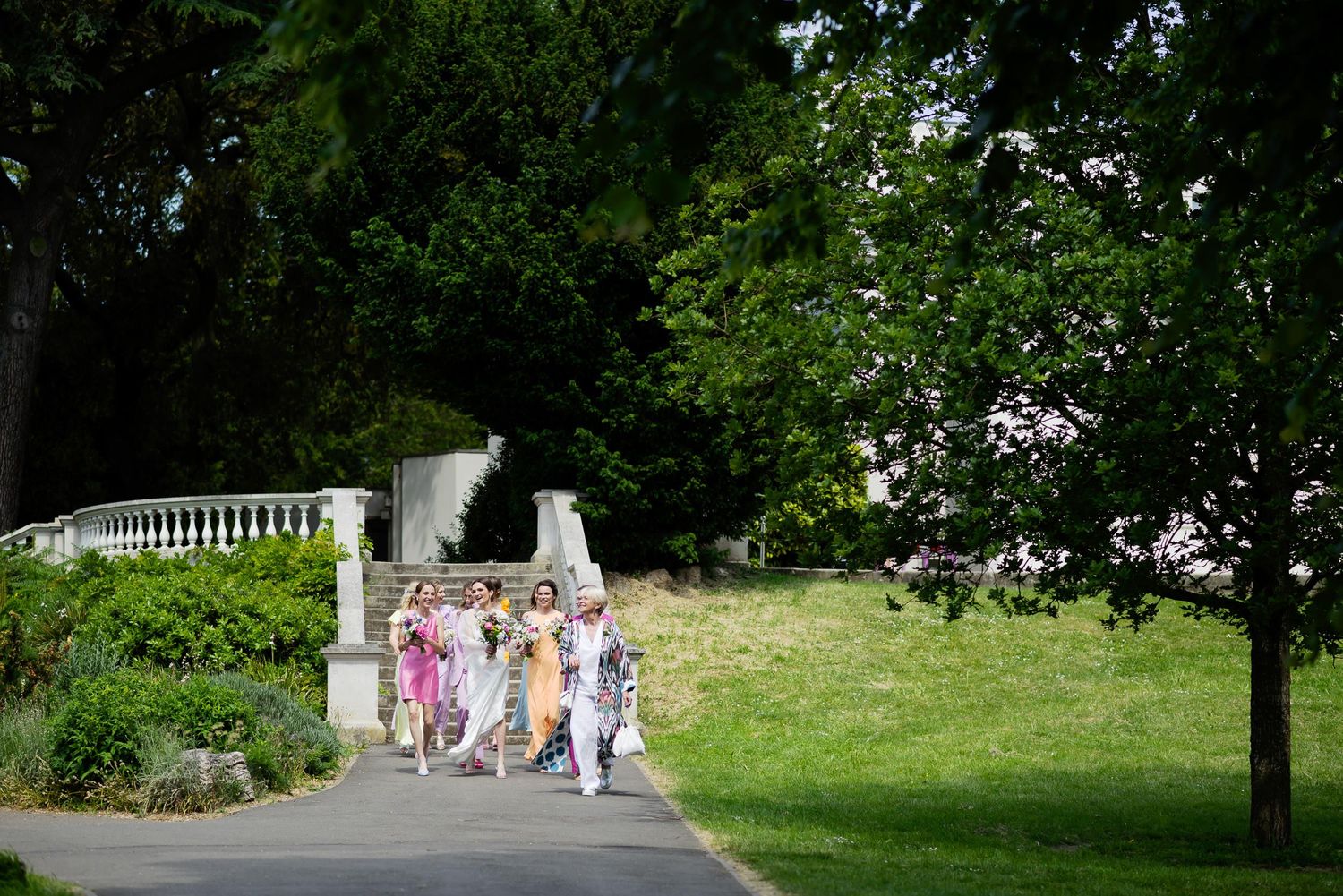 Group walking along garden path wearing colorful summer dresses.
