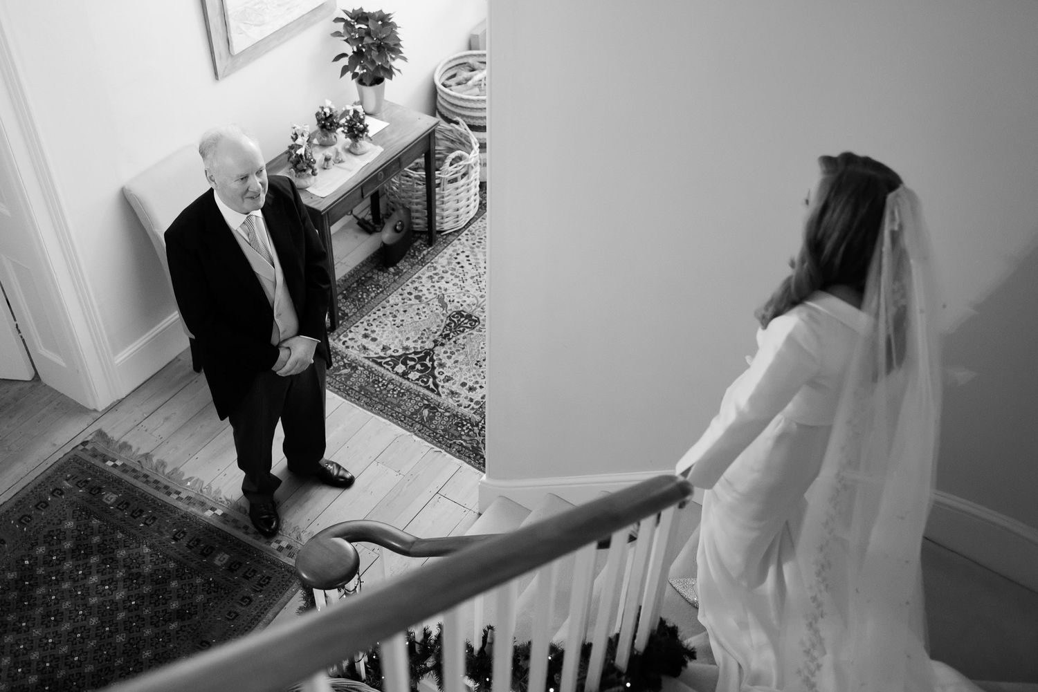 Black and white photo of bride and father sharing moment on wedding day staircase.
