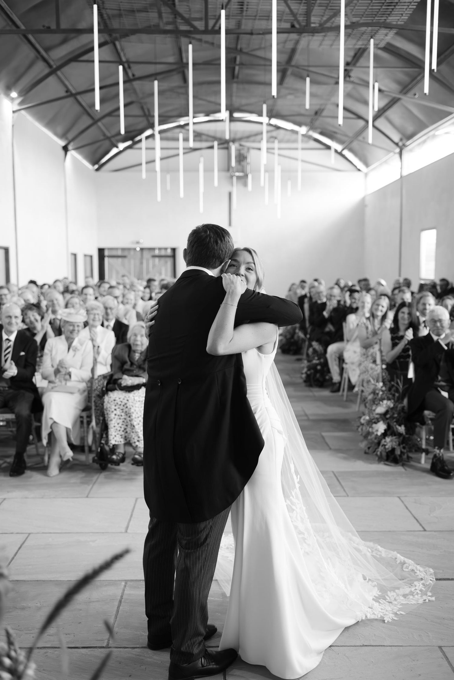 Black and white wedding dance sequence showing a couple twirling in an indoor venue with high ceilings.