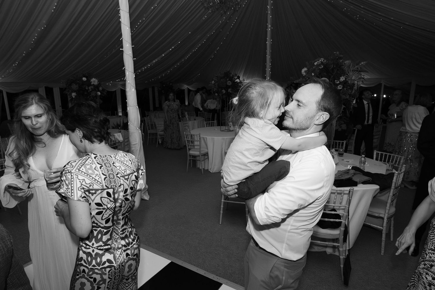 People dancing and celebrating at a dimly lit indoor wedding reception.