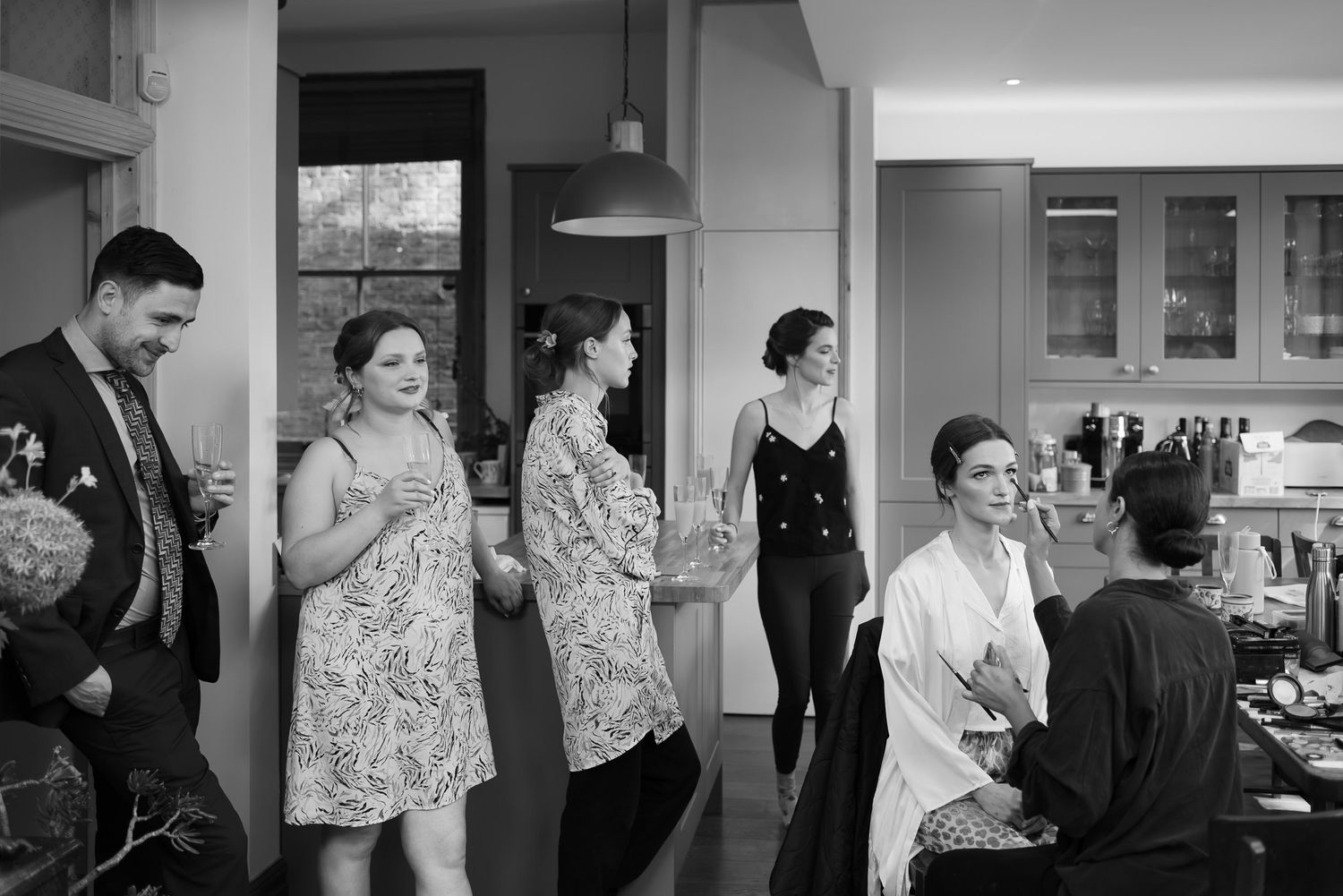 A series of black and white photos showing people in a kitchen or dining area interacting and socializing together.