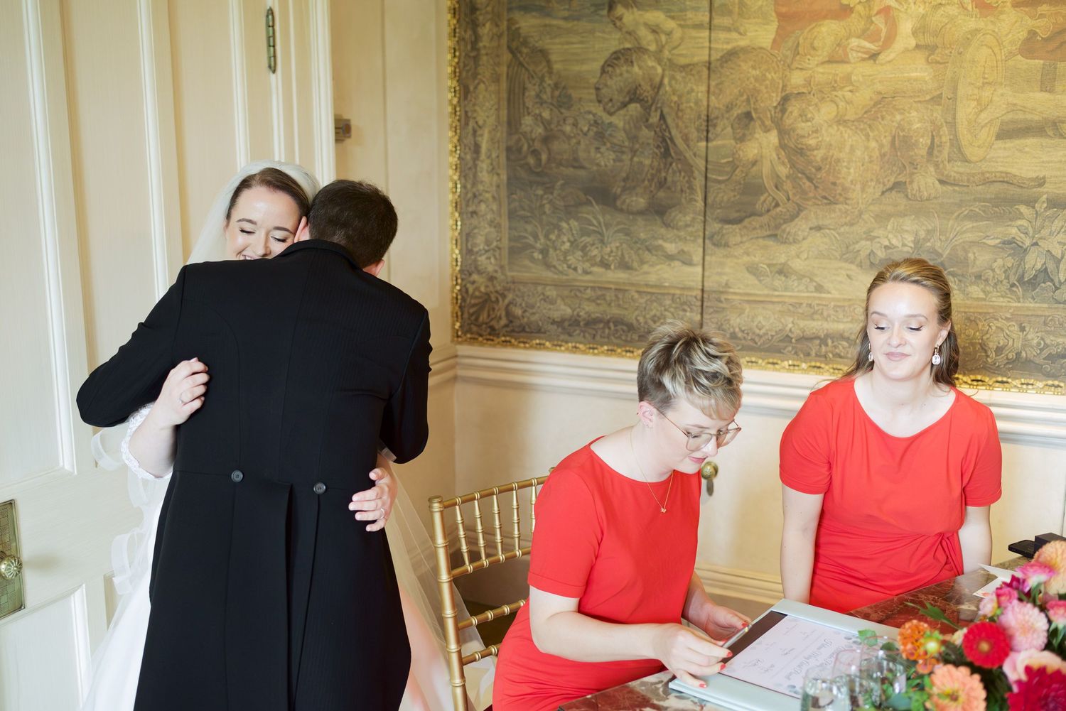 Wedding celebration in elegant room with red accents and decorative wall tapestries.