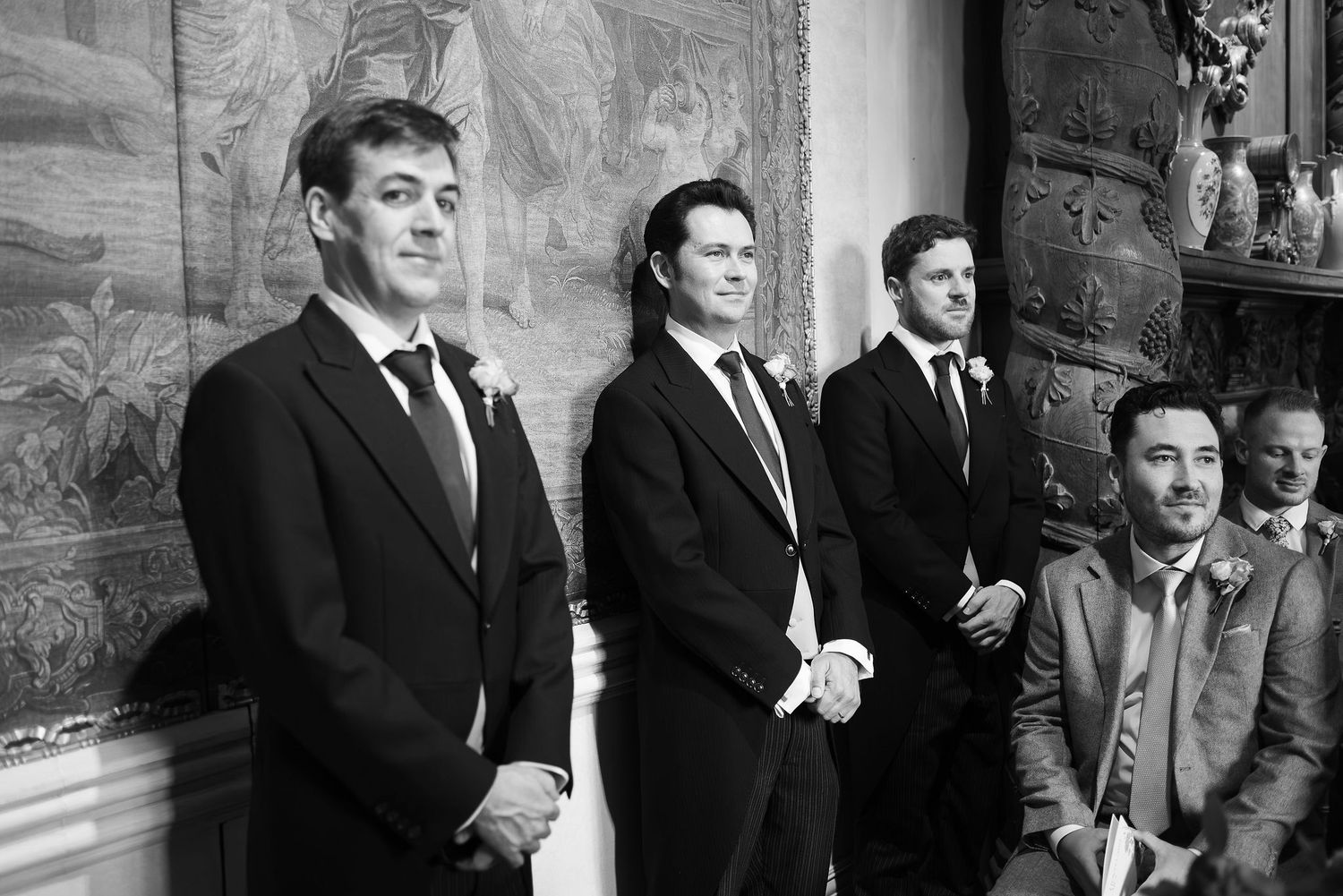 Groomsmen in dark suits stand together smiling during a wedding celebration.