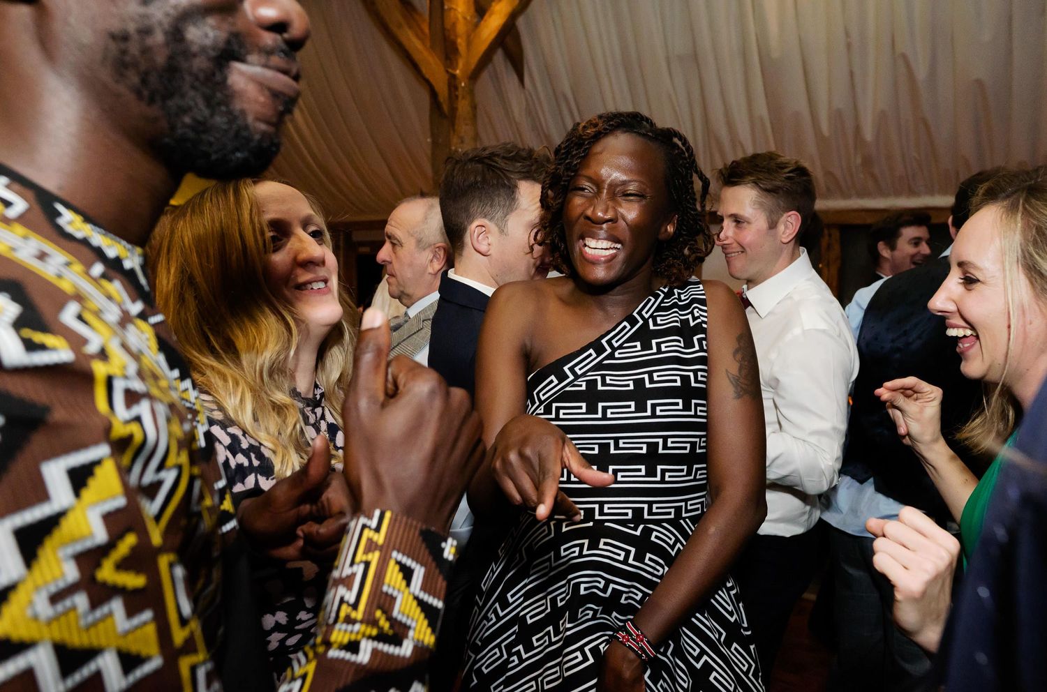 Lively wedding reception scene with guests dancing and laughing together.