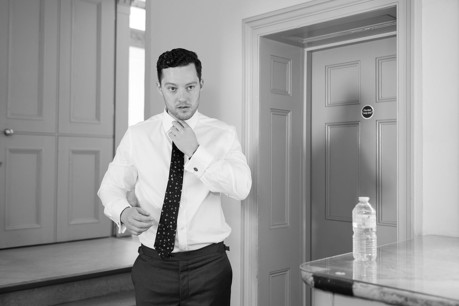 A series of five black and white photographs showing someone in business attire posing in an office setting.