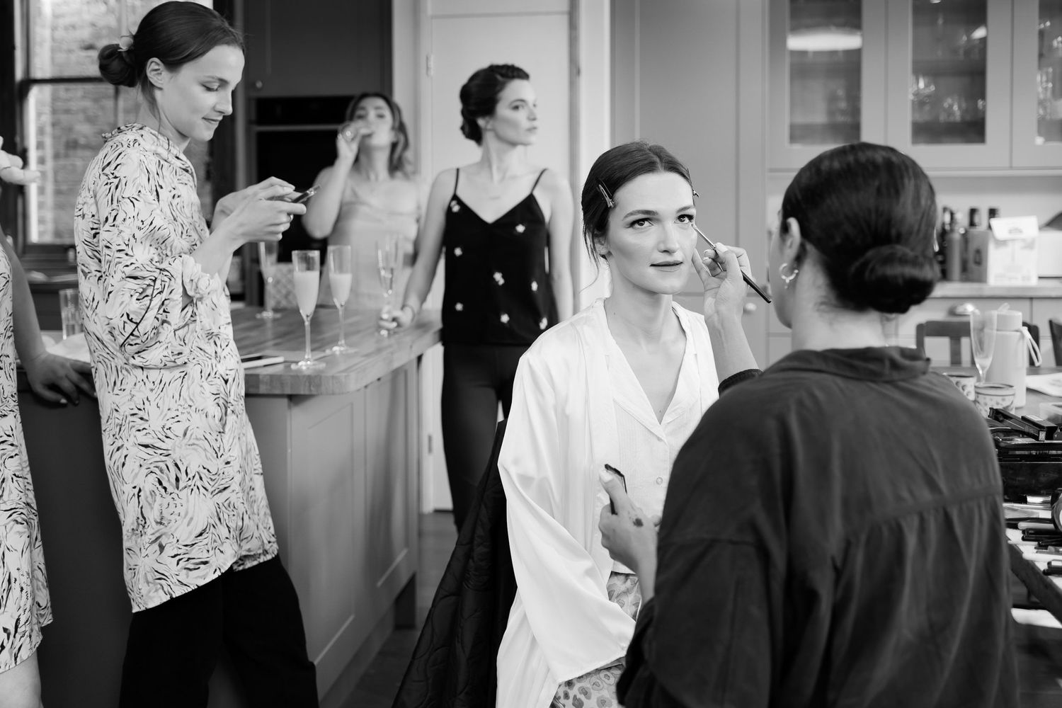Black and white candid photograph of wedding preparations in a kitchen setting.