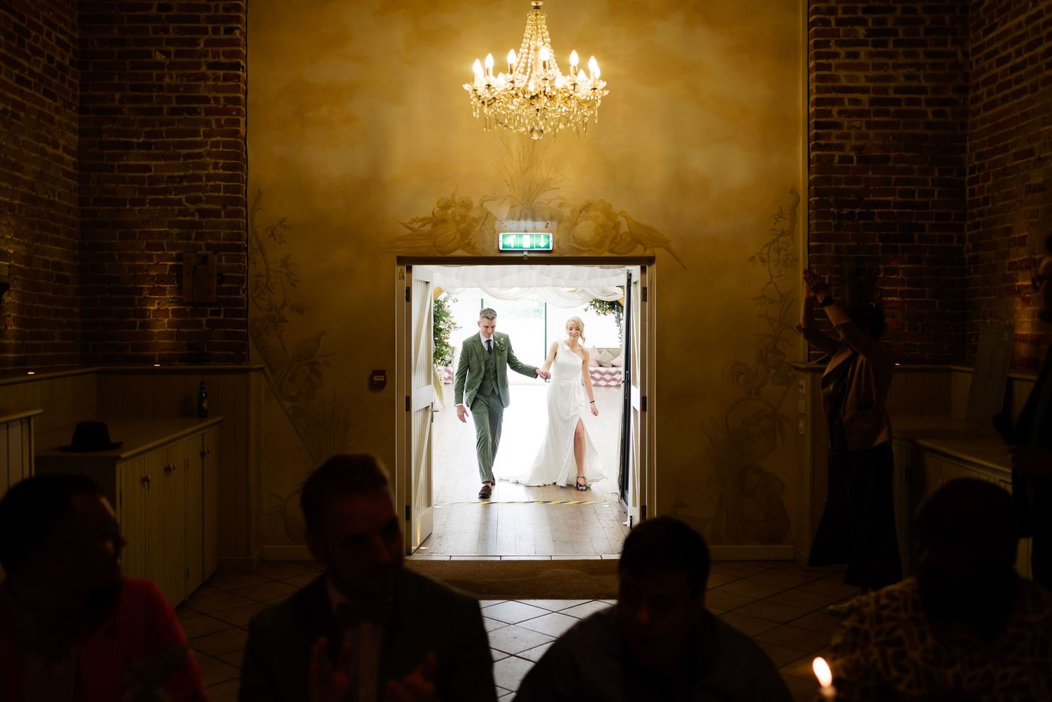 Dramatic entrance through doorway with chandelier lighting at wedding venue.