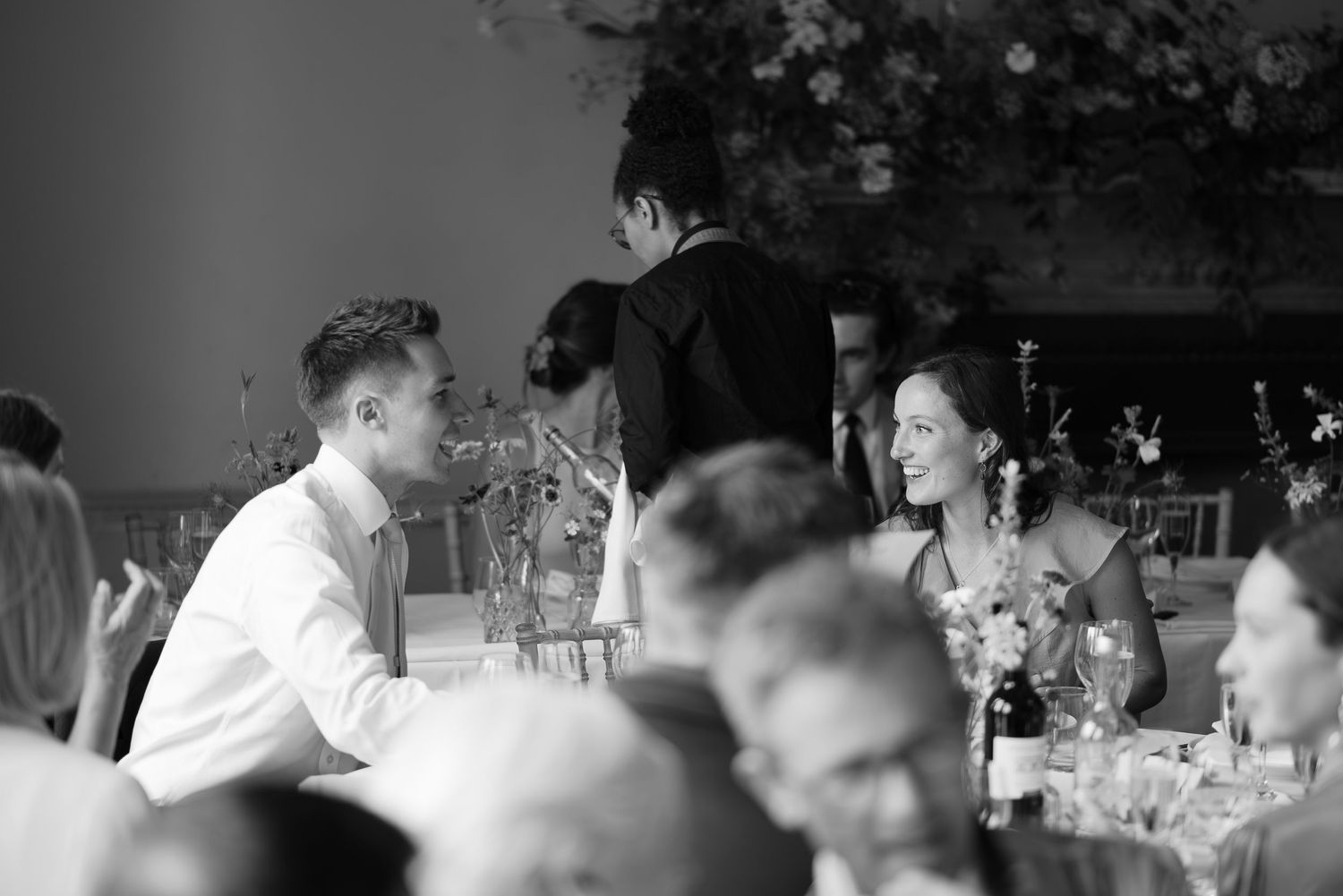 Black and white photo of wedding guests enjoying a reception dinner.