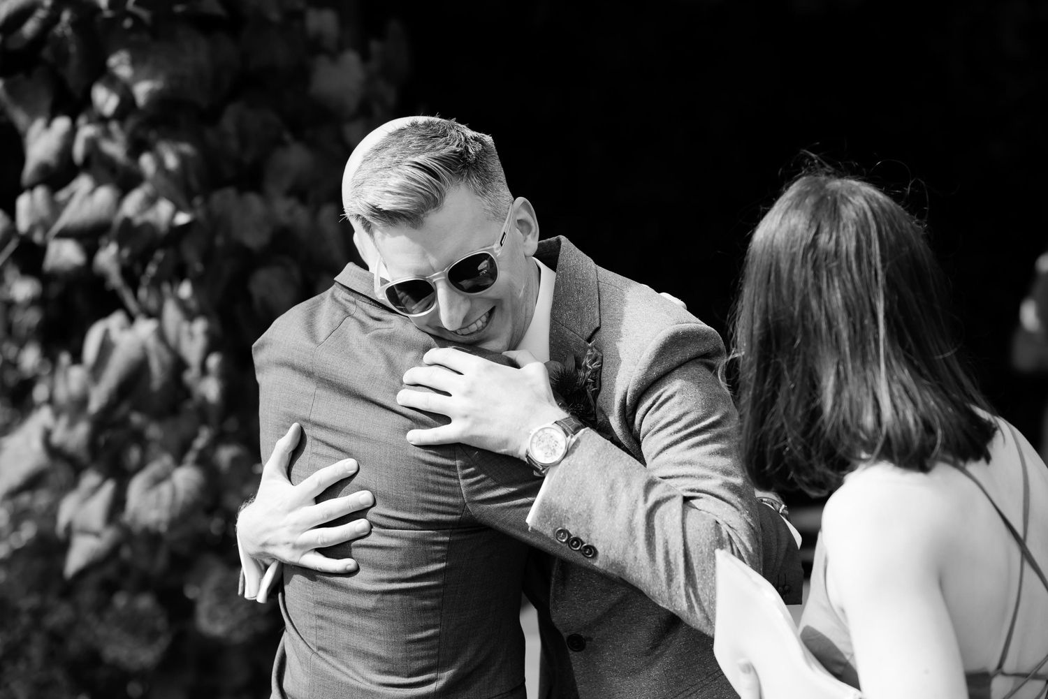 Black and white capture of emotional embrace during wedding celebration.