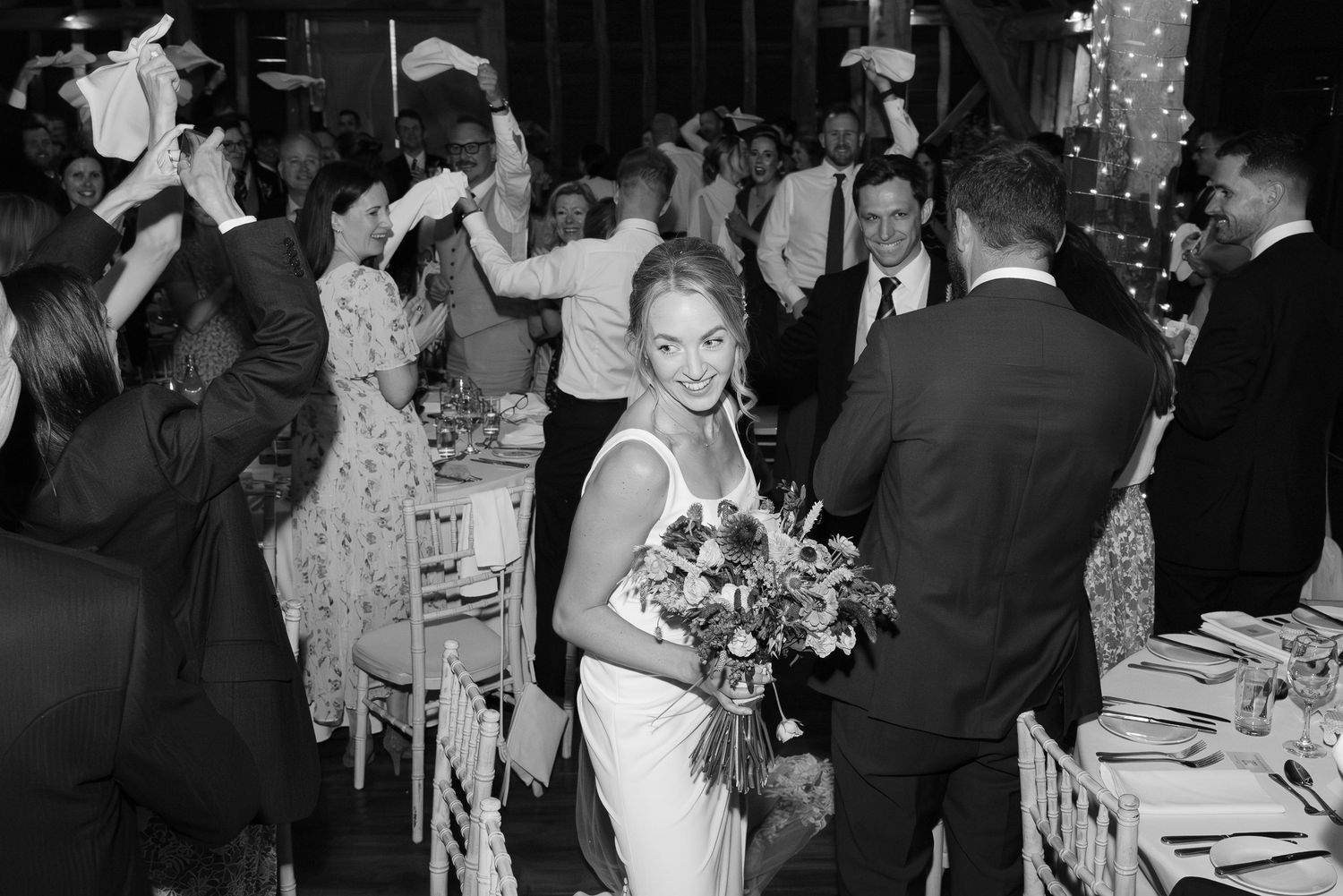 Guests dancing and celebrating at a lively wedding reception in black and white photography.