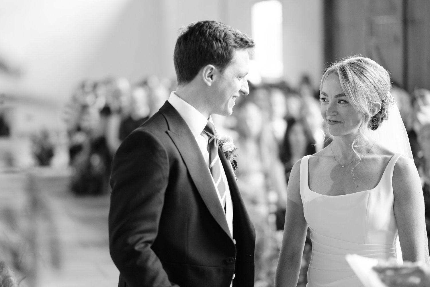 Bride and groom smile at each other during their ceremony at Manor Barn, Cambridge.