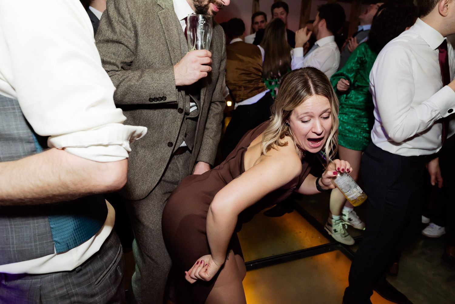 Wedding guest bending low during an energetic dance move at the reception.