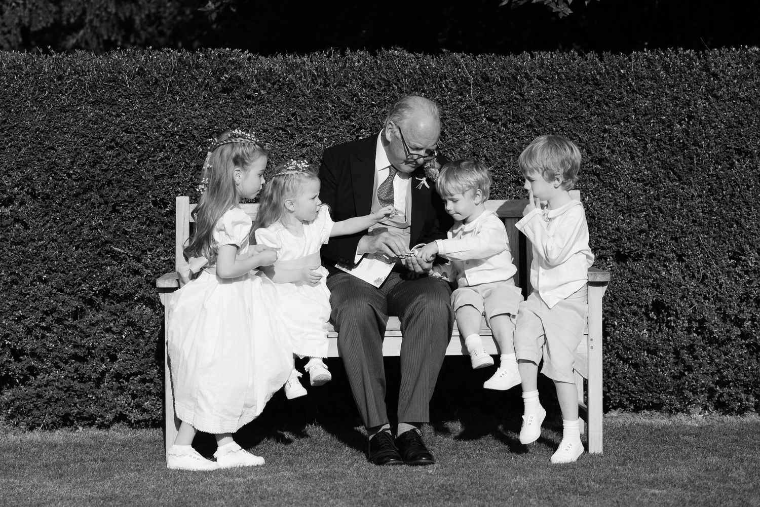 A sequence of black and white photographs showing a dog and child playing together in a garden setting.