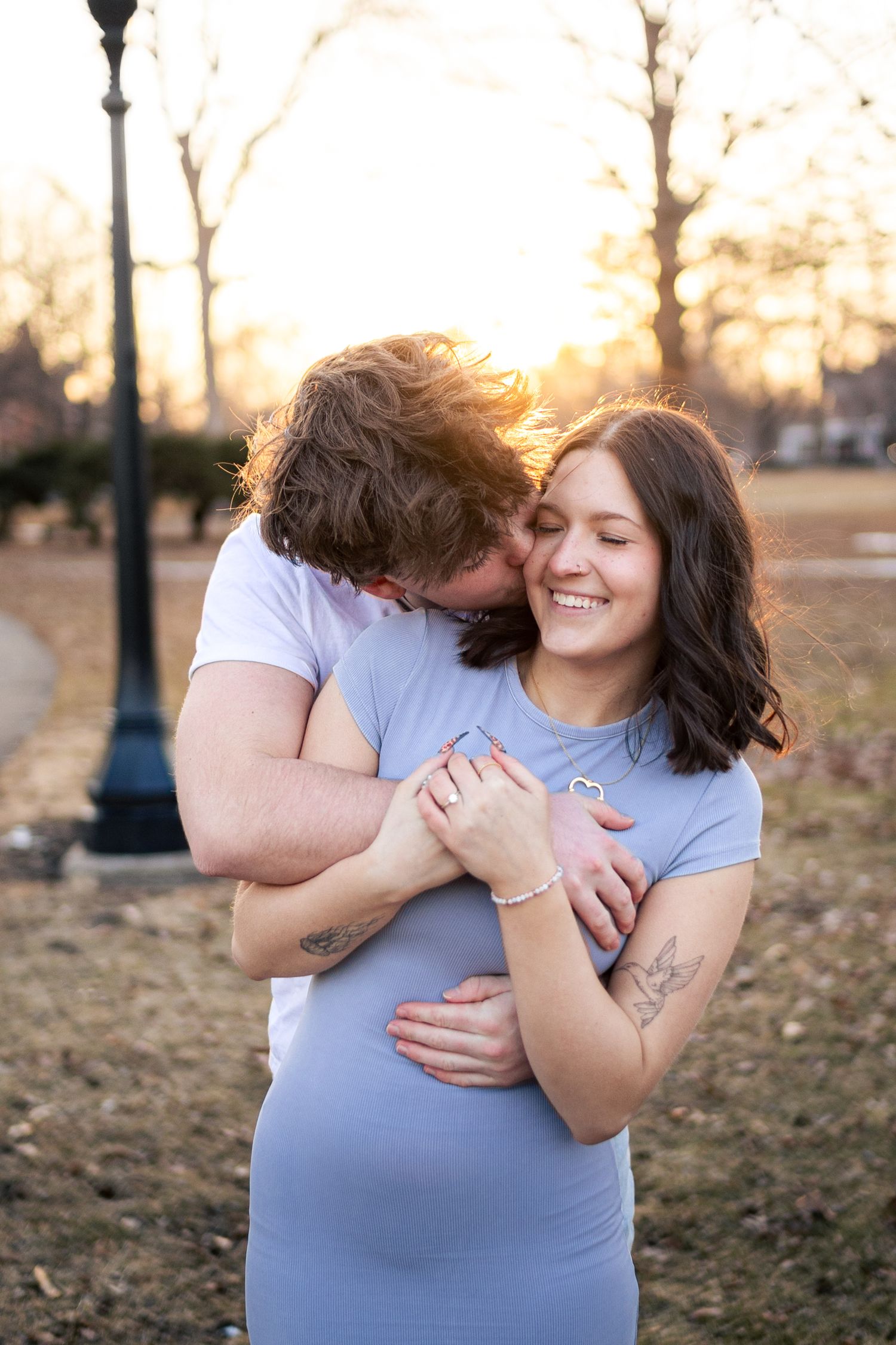 Couples photo in West Side Park capturing a man hugging and kissing his girlfriend. JDalbey Photography — couples portraits in Champaign IL.